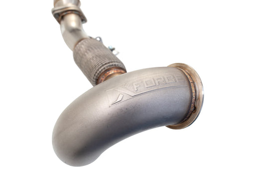 Close-up of a polished stainless steel exhaust pipe with 'XFORCE' logo, featuring a curved design and welded sections.